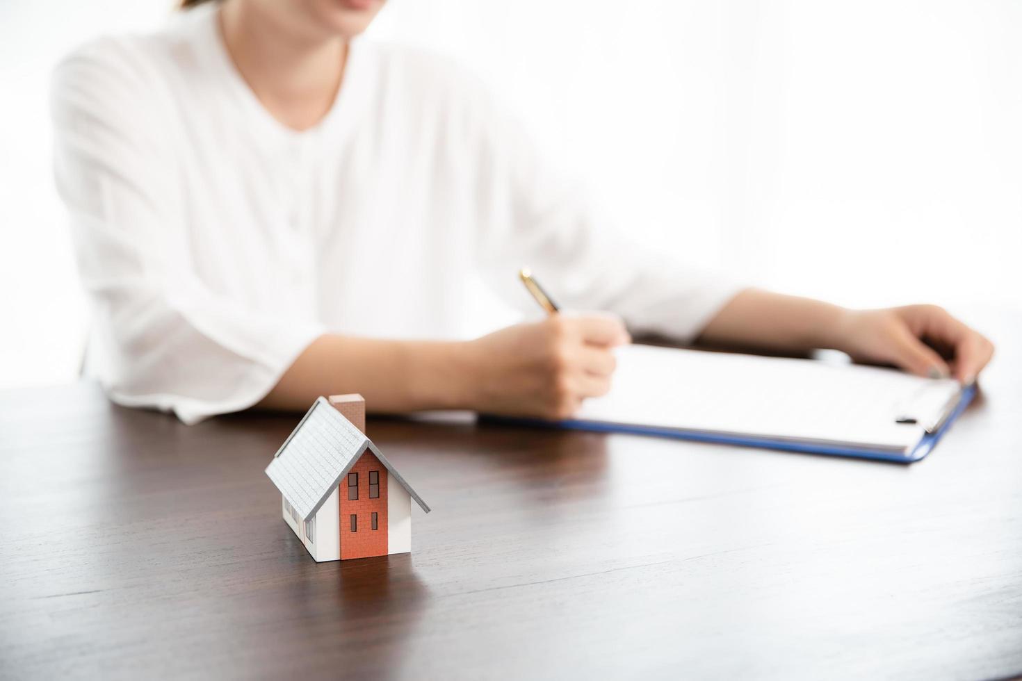 eine Frau, die einen Wohnungsbaudarlehensvertrag unterzeichnet, während sie einen Stift hält foto