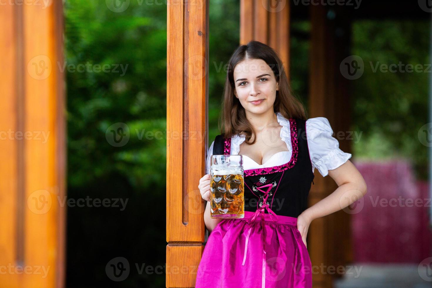 sexy russische frau im bayerischen kleid, das bierkrüge hält. foto