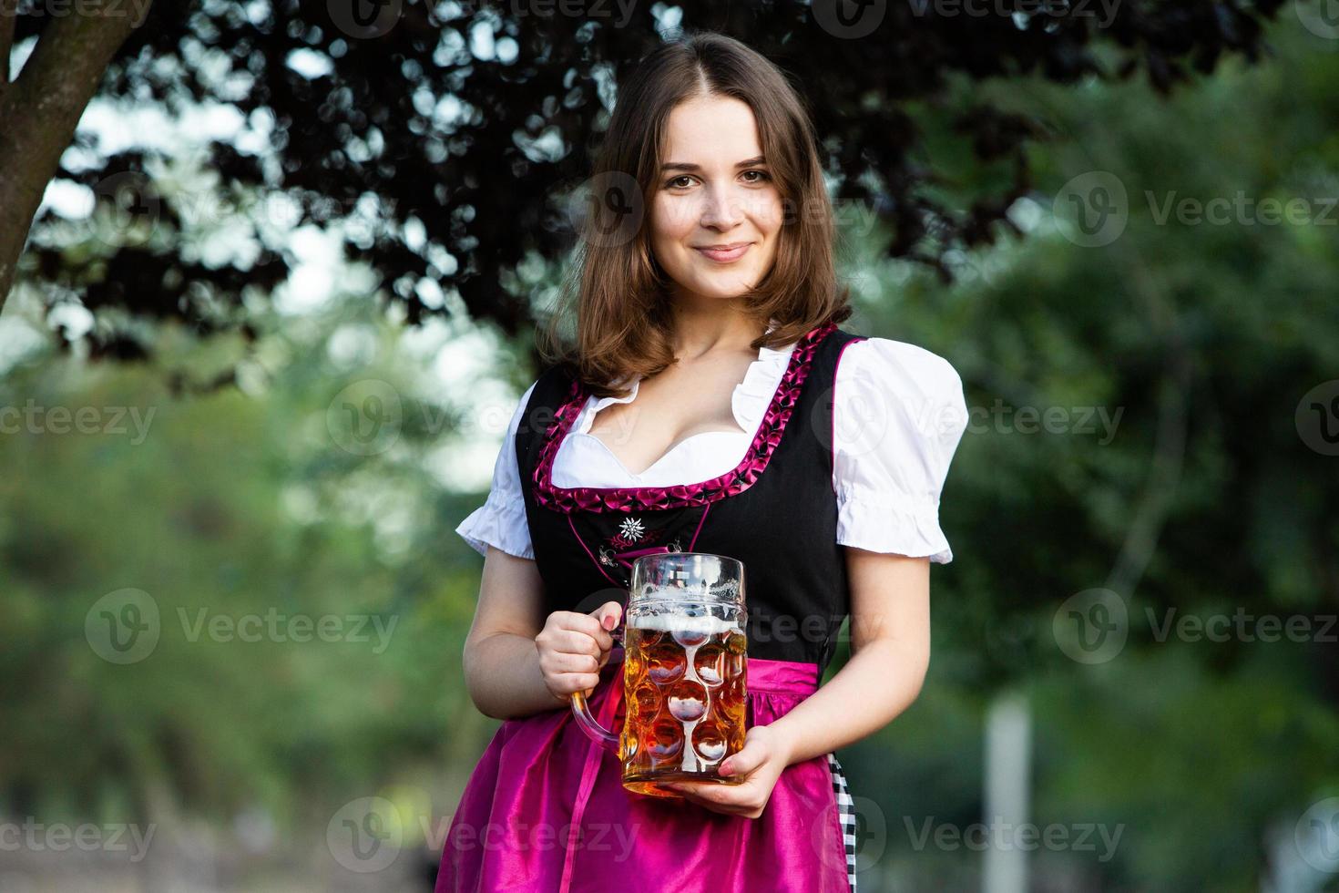 sexy russische frau im bayerischen kleid, das bierkrüge hält. foto