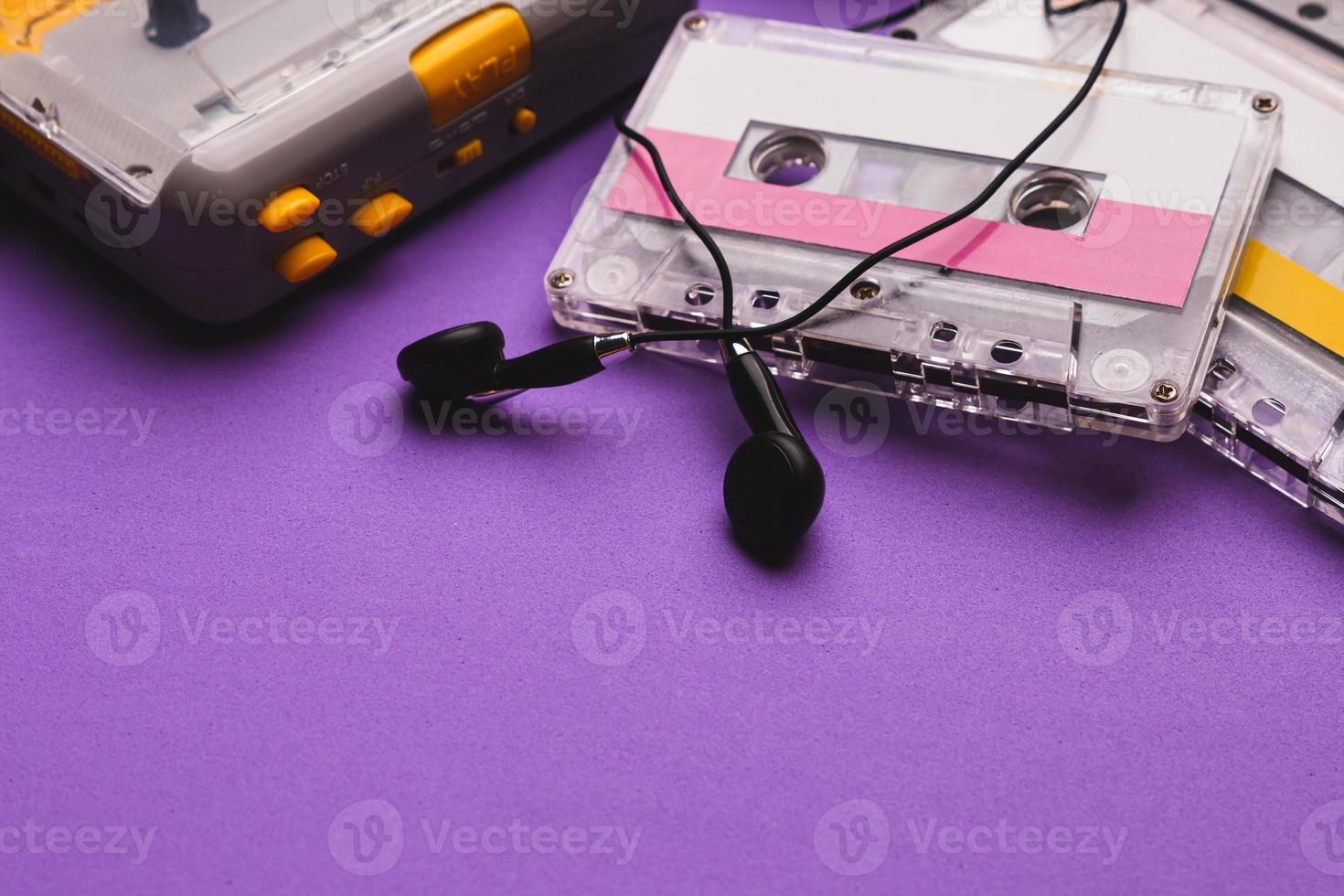 kassettenspieler mit kopfhörern und kassetten auf violettem hintergrund. Platz für Text kopieren. foto