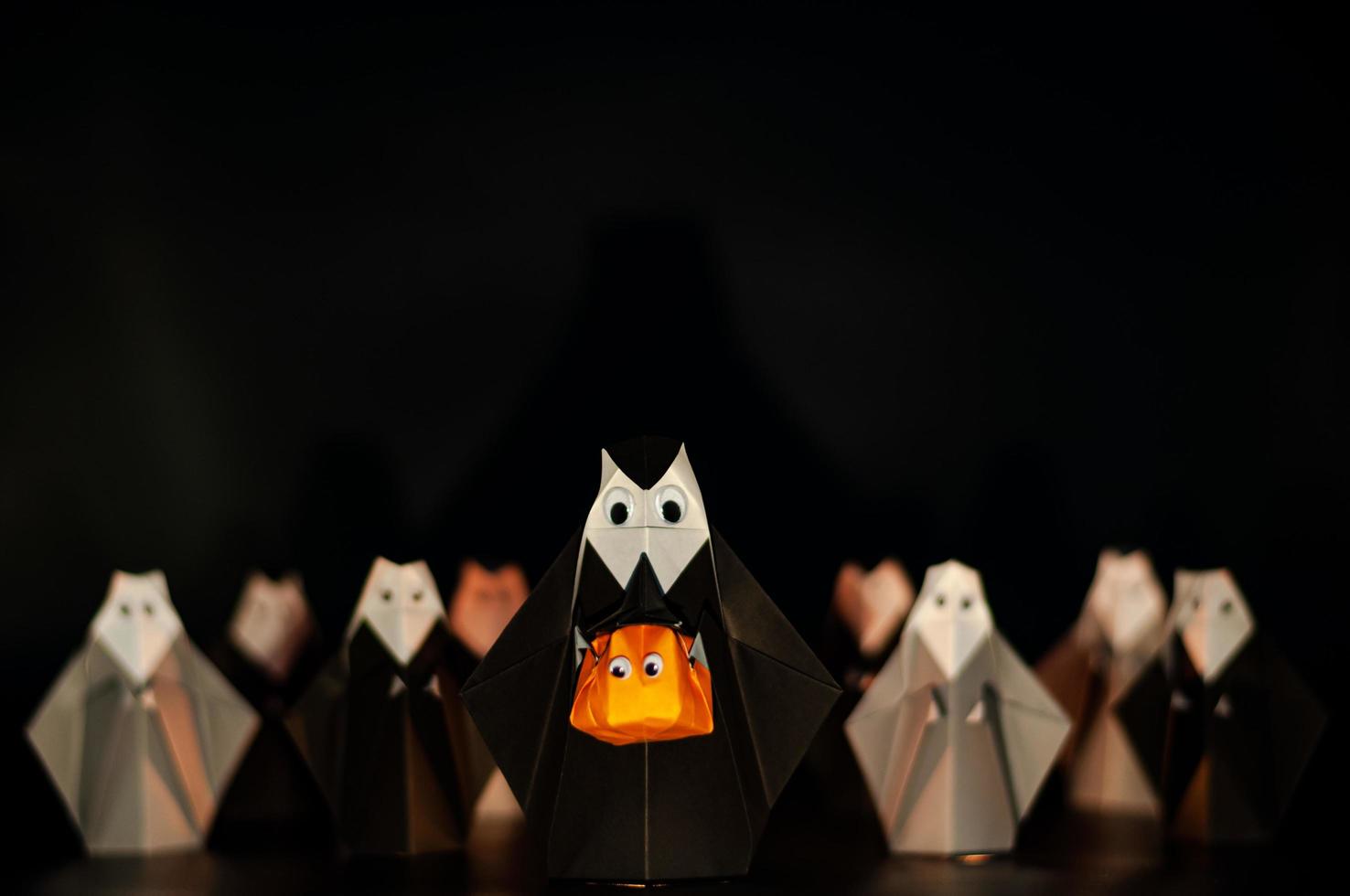 die halloween origami oder papierfaltende nonne, die kürbiskopf hält, jack o laterne aus gefaltetem papier mit vielen nonnen im hintergrund. foto