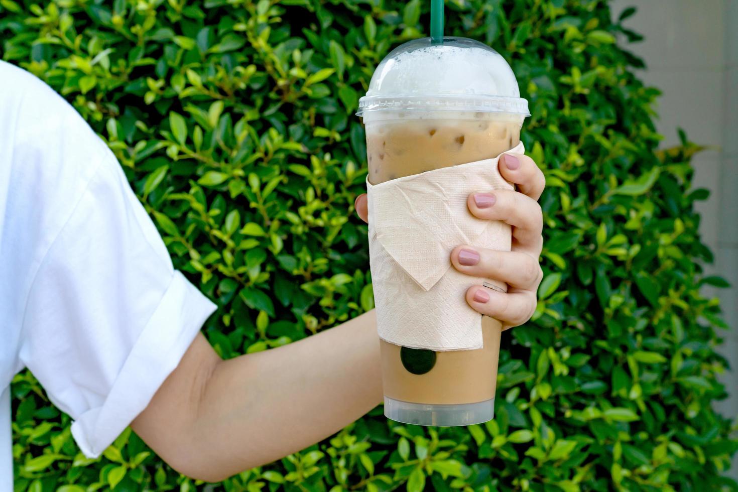 frauenhand, die den eiskaffee im garten hält foto