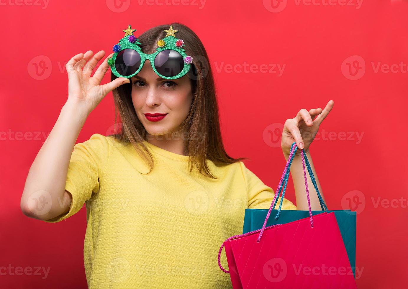 Frau mit Weihnachtsfeiergläsern und Einkaufstüten foto