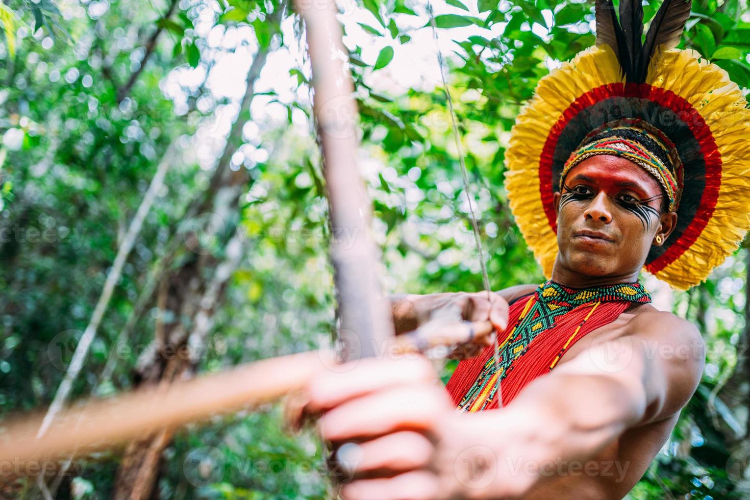 Indianer vom Pataxo-Stamm mit Pfeil und Bogen. brasilianischer Indianer mit Federschmuck und Halskette foto