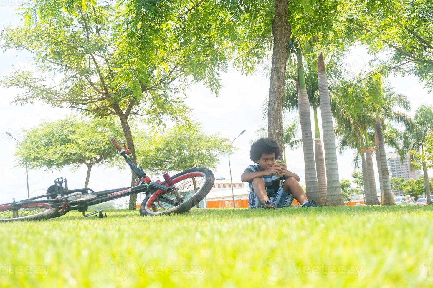 Junge sitzt neben einem Fahrrad foto