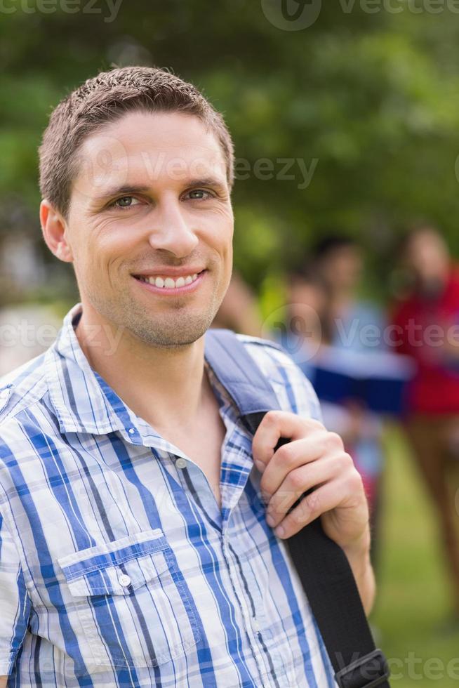 glücklicher Student, der draußen auf dem Campus in die Kamera lächelt foto