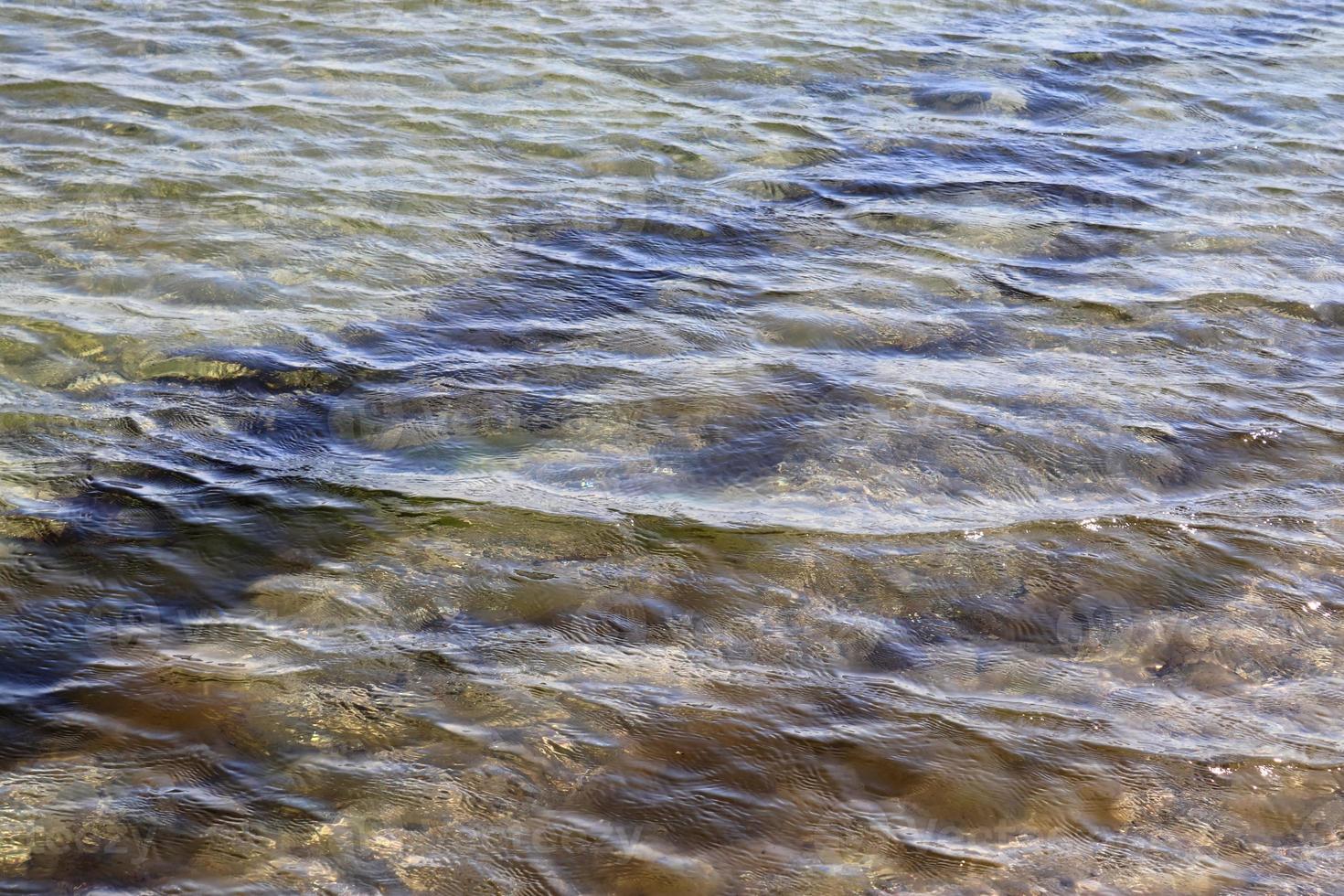 detaillierte nahaufnahme auf wasseroberflächen mit wellen und wellen und das sonnenlicht, das an der oberfläche reflektiert wird foto