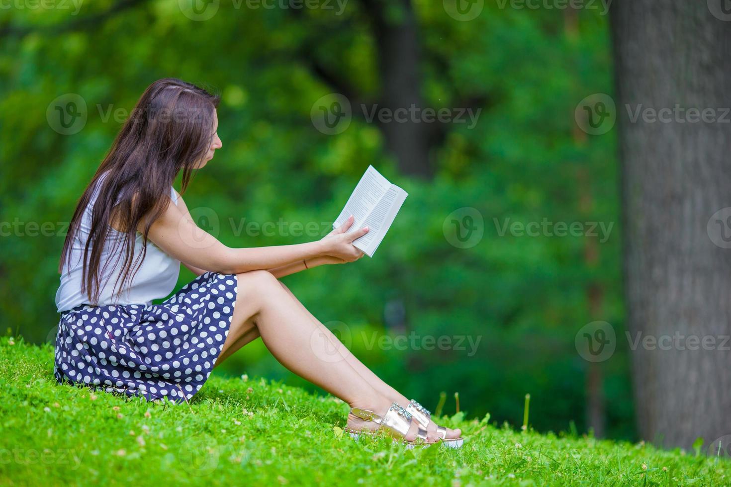 junges Mädchen, das ein Buch draußen im Park liest foto