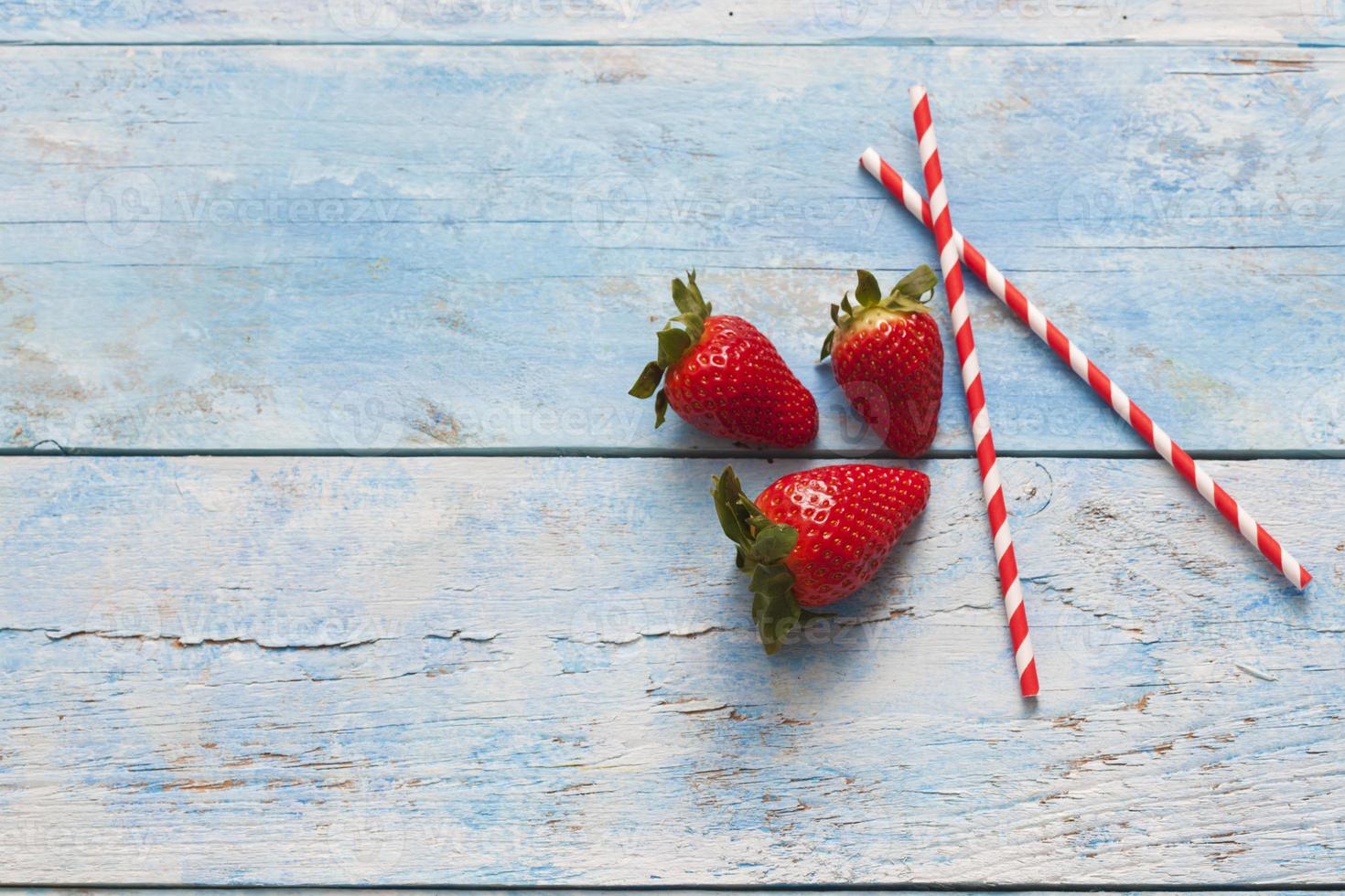 Erdbeeren, Trinkhalme, blaues Holz foto