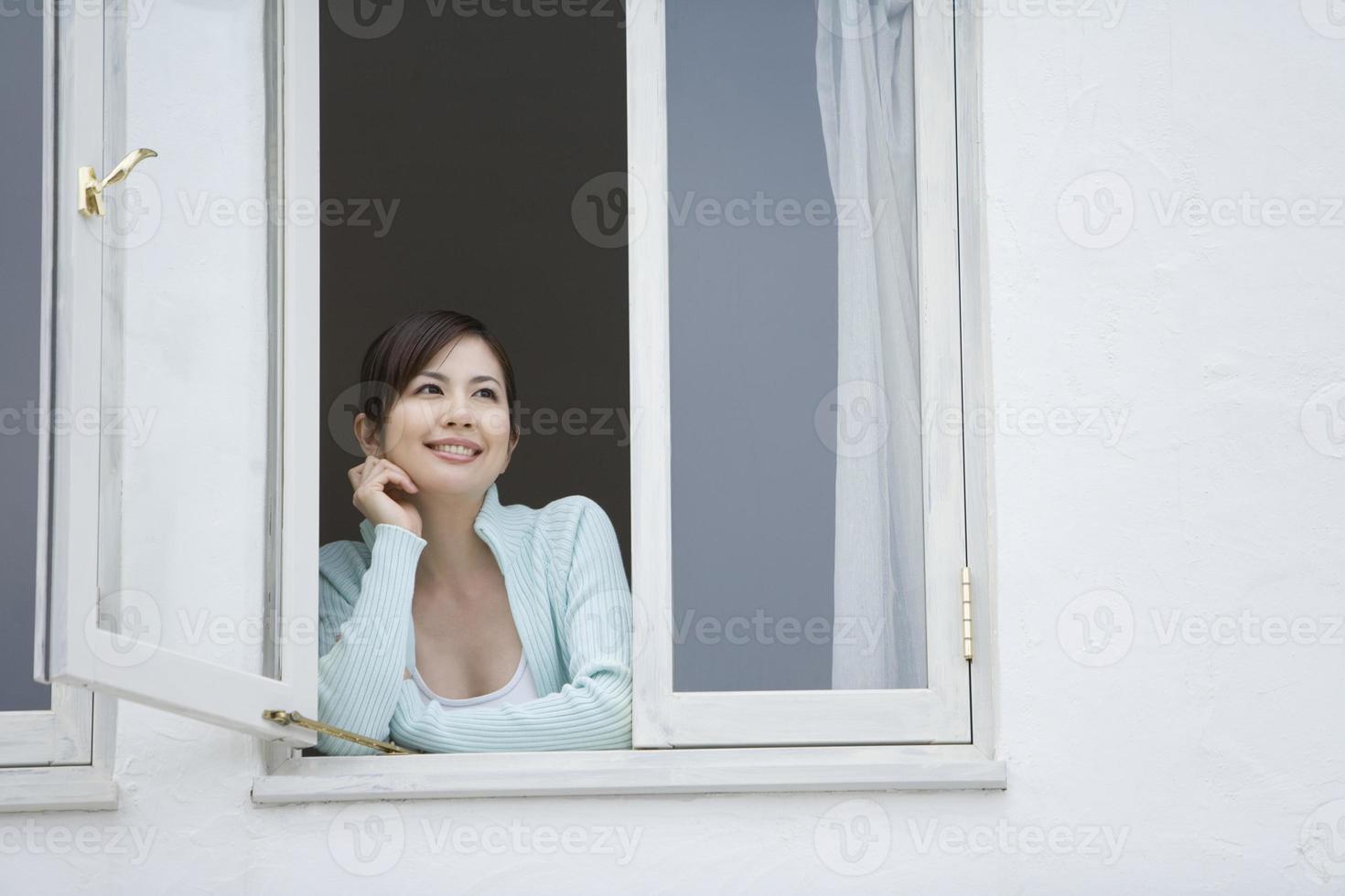 Frau, die durch Fenster lächelt foto