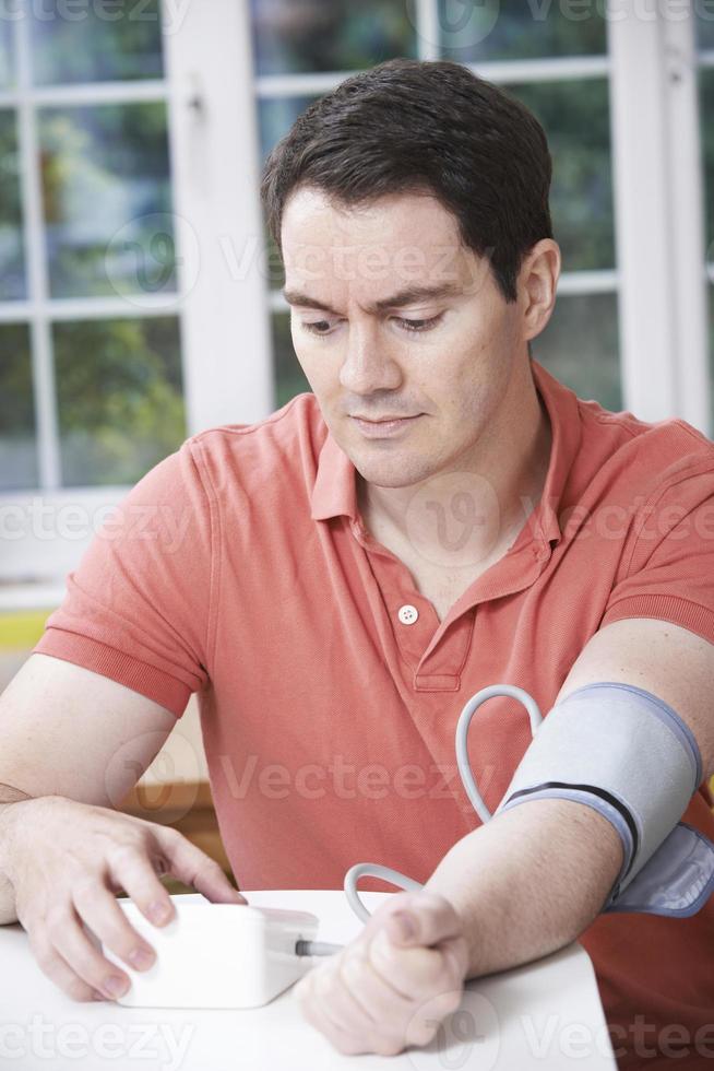 Mann, der zu Hause den Blutdruck misst foto