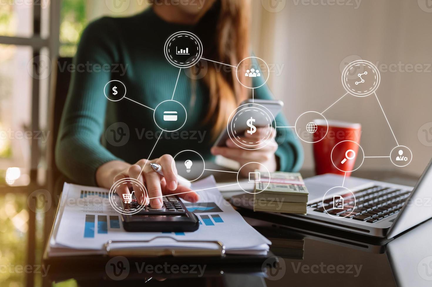 Hände der Frau mit Handy im modernen Büro mit Laptop und digitalem Tablet foto