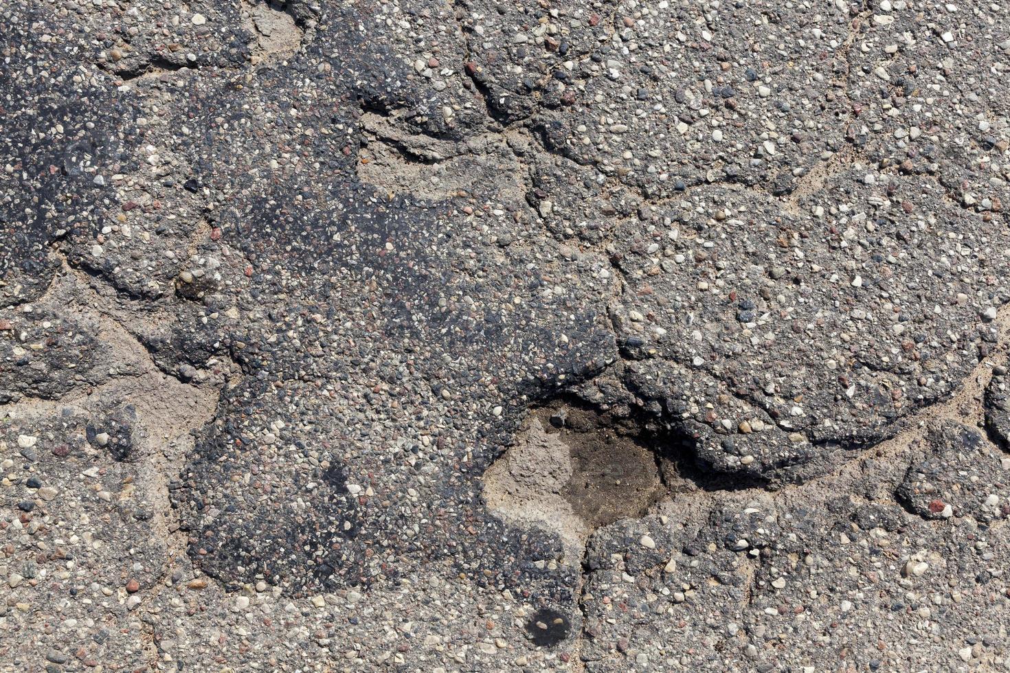 eine Asphaltstraße mit vielen Löchern und Schlaglöchern foto