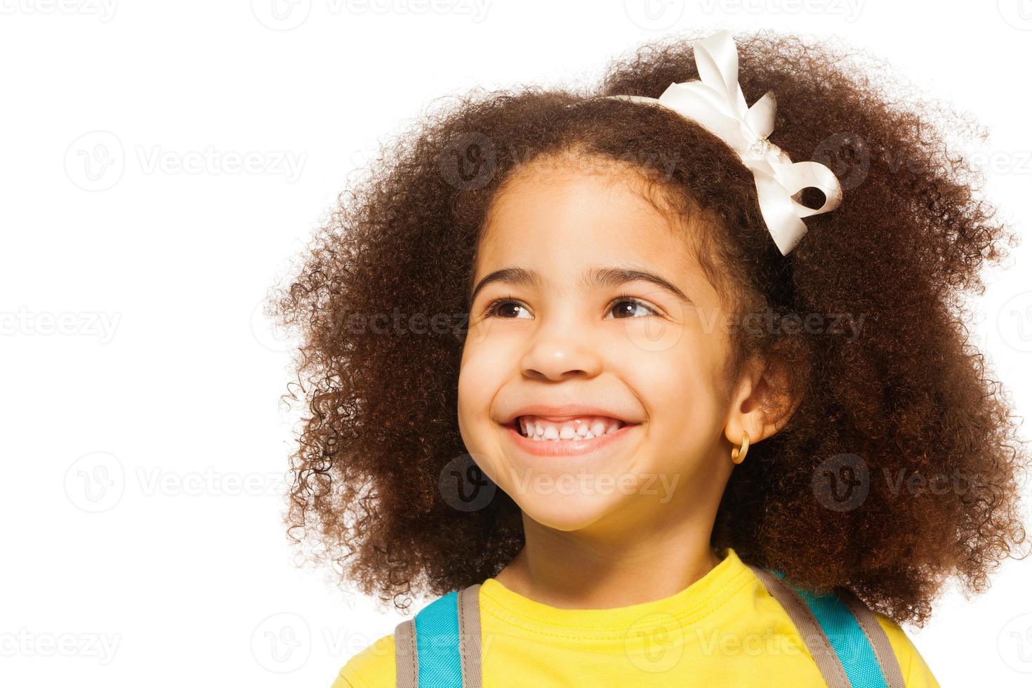 fröhliches afrikanisches Mädchen, das weißen Bogen im Haar trägt foto