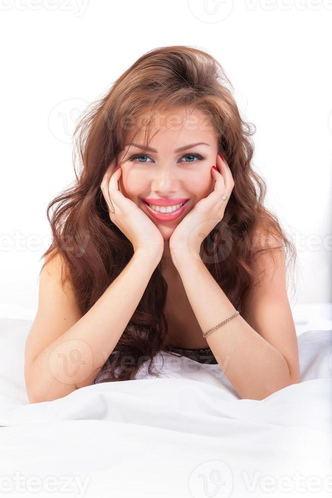 Porträt der schönen jungen Frau, die im Bett liegt foto