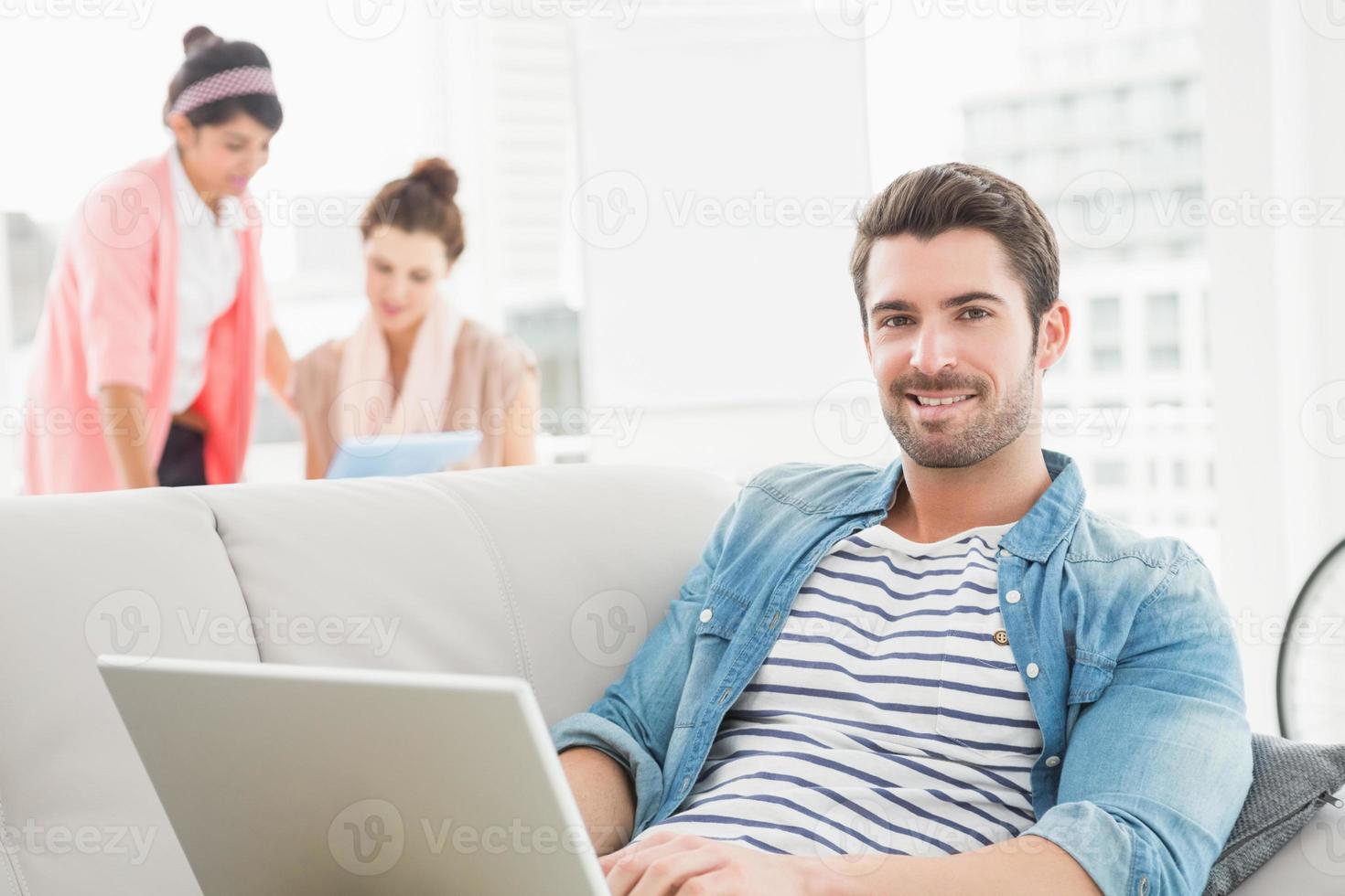 fröhlicher Geschäftsmann mit Laptop auf Sofa foto