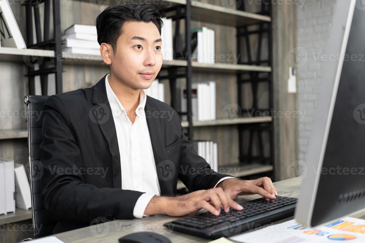 Porträt eines Geschäftsmannes, der einen Computer am Arbeitsplatz in einem Büro verwendet. positiver Geschäftsmann, der in den Bildschirm des Computers lächelt. foto