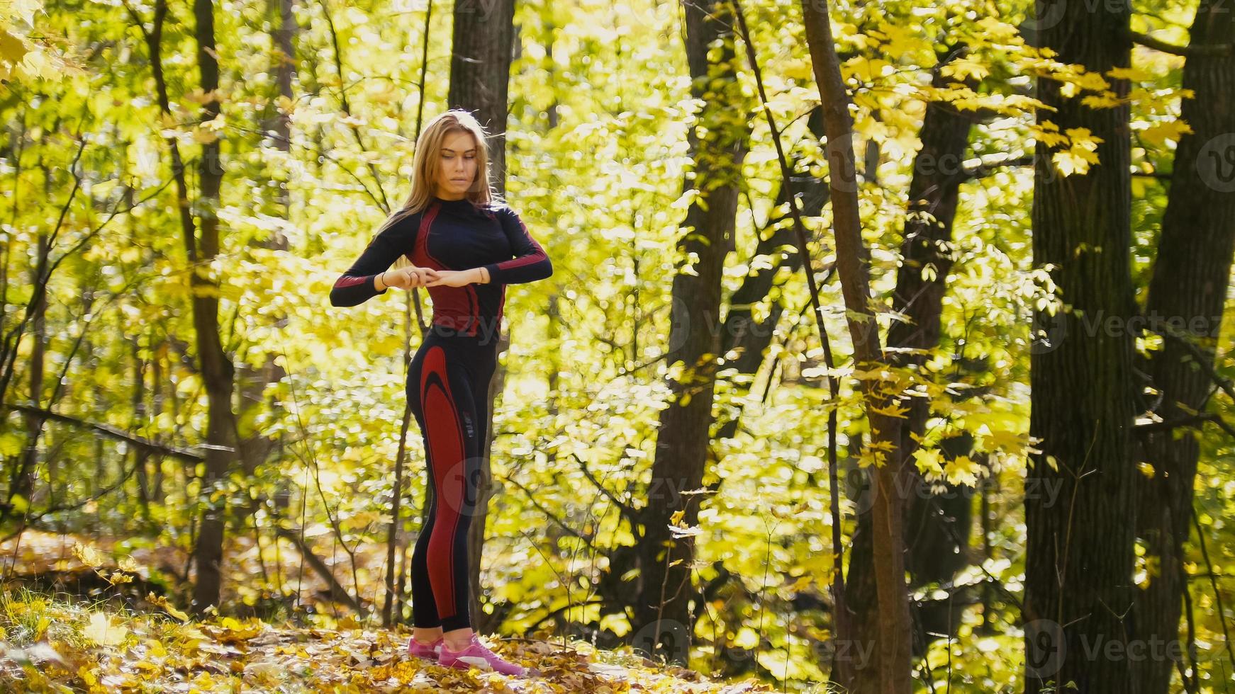 Frau macht Fitnessübungen im Freien. Weibchen, das sich im herbstlichen Wald ausdehnt. schlankes Mädchen beim Training foto