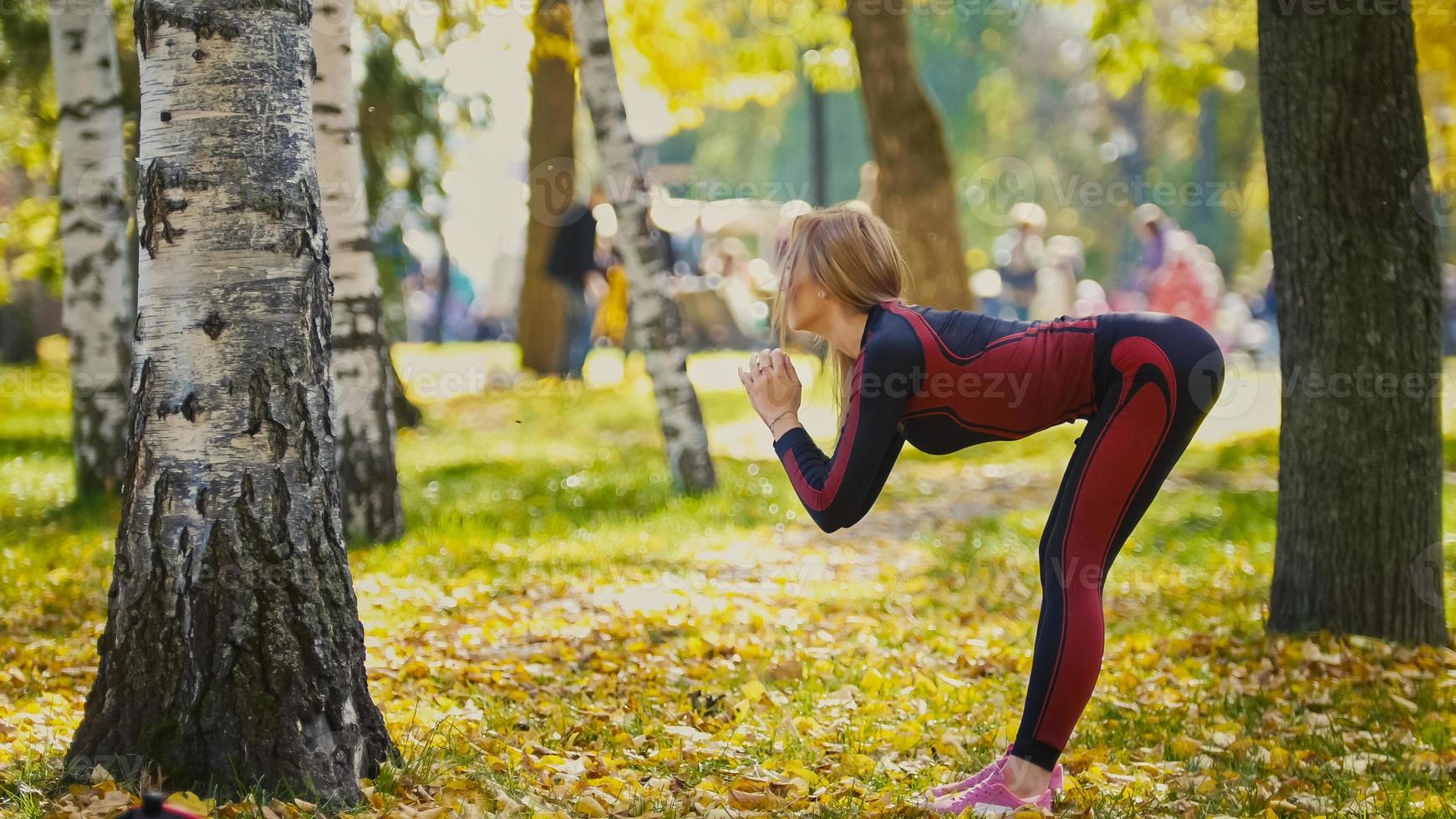 sexy attraktive weibliche blonde Bikini-Fitness-Model Stretching im Herbst Park auf dem Boden bedeckt gelbe Blätter - die Neigung des Körpers foto