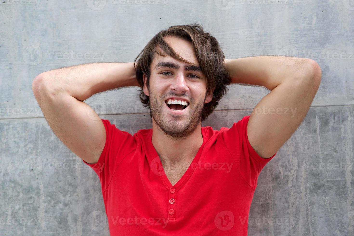 junger Mann lacht mit der Hand im Haar foto