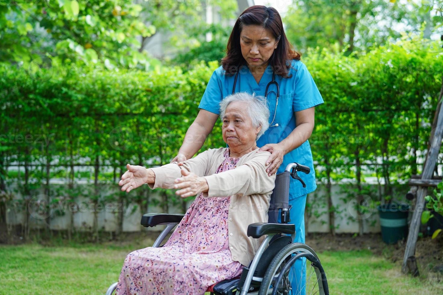 asiatische ältere Frau Behinderung Patientenübung im Rollstuhl mit Arzt im Park, medizinisches Konzept. foto