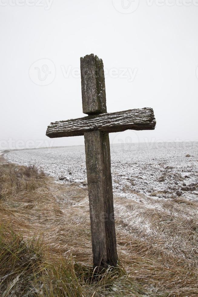 Altes hölzernes religiöses Kreuz auf dem Feld foto