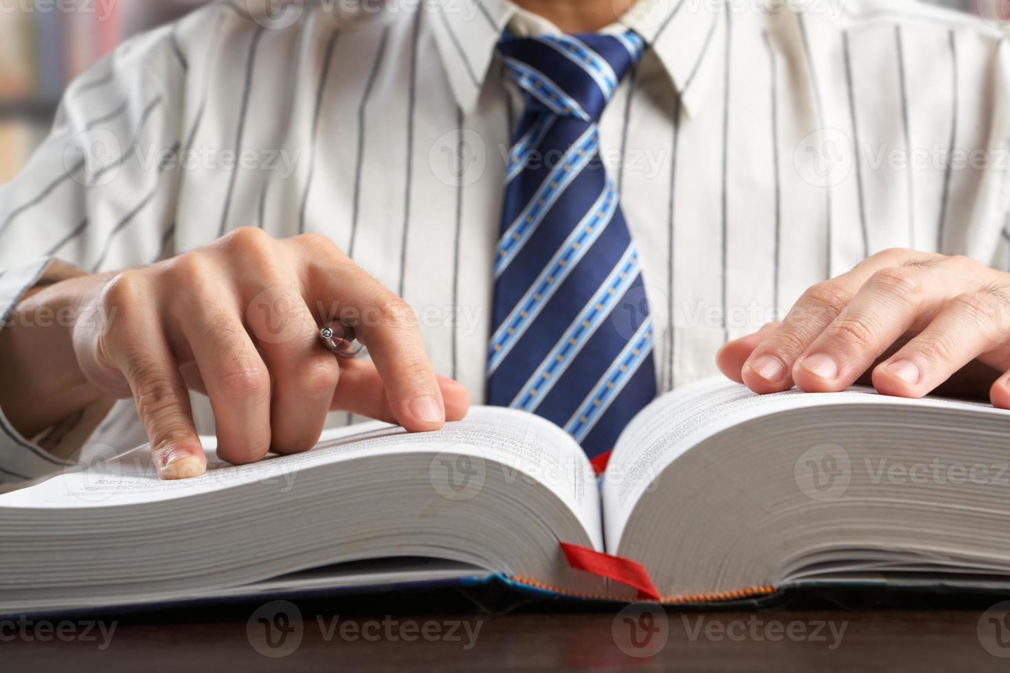 Geschäftsmann und / oder Professor, der ein Lehrbuch liest foto