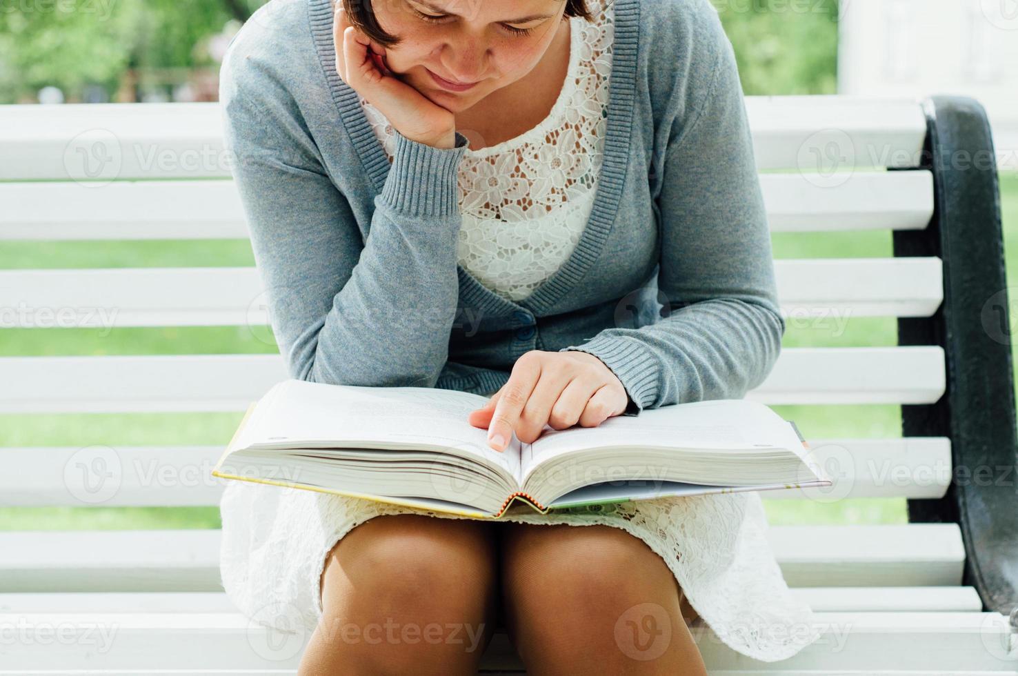 junge Frau liest auf einer Bank im Park foto