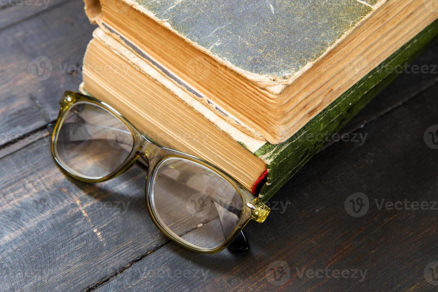 Vintage Lesebrille und das Buch auf hölzernem Hintergrund foto