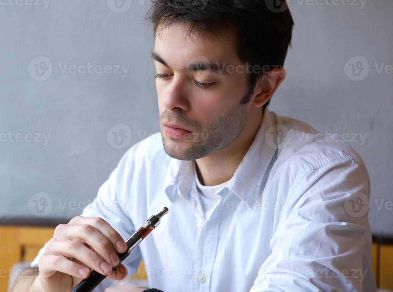 junger Mann, der elektrische Zigarette raucht foto