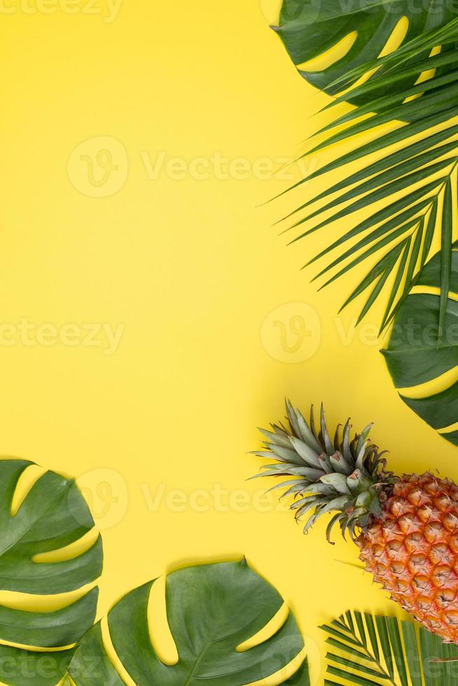 Schöne Ananas auf tropischen Palmen-Monstera-Blättern isoliert auf hellem pastellgelbem Hintergrund, Draufsicht, flache Lage, Overhead über Sommerfrucht. foto