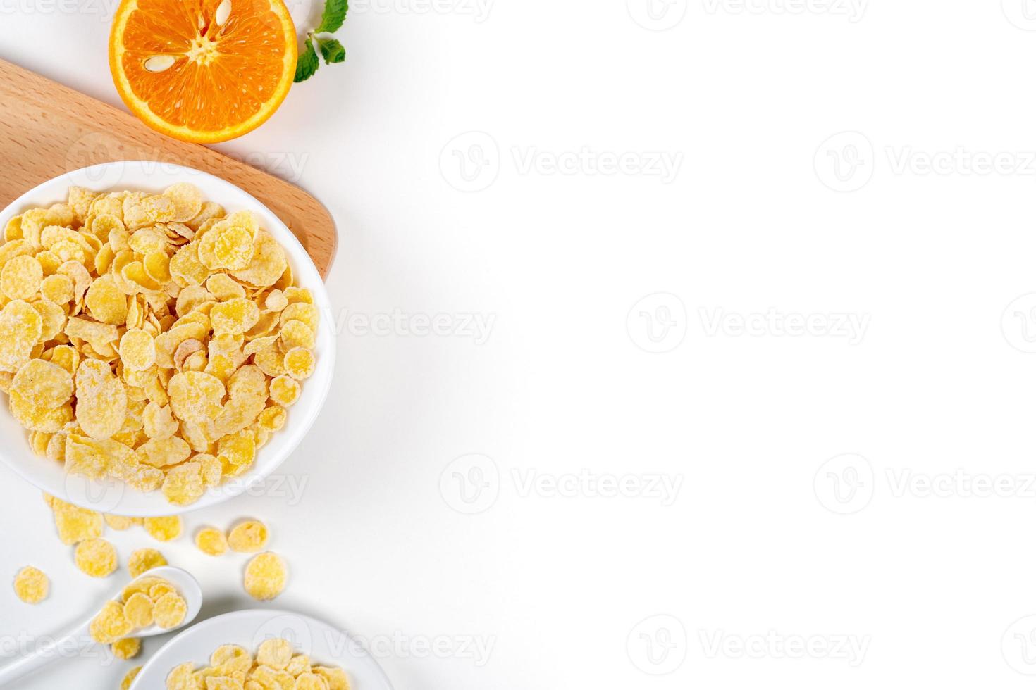 cornflakes schüssel süßigkeiten mit milch und orange auf weißem hintergrund, draufsicht, flaches lagoverlay, frisches und gesundes frühstücksdesignkonzept. foto