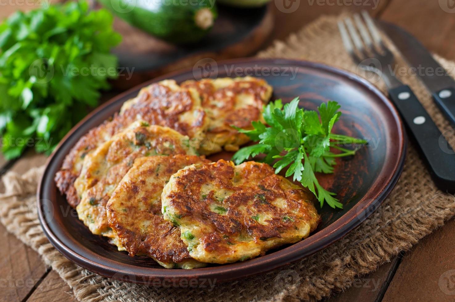 Zucchini-Pfannkuchen mit Petersilie auf einem Holztisch foto