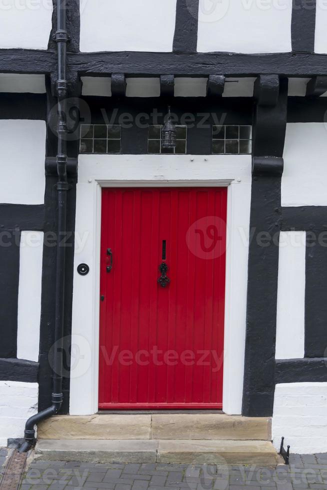 rote Haustür in einem Fachwerk-Tudorhaus foto