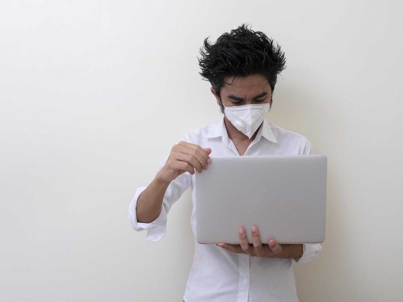 geschäftsmann in medizinischer gesichtsmaske arbeitet zu hause am laptop foto