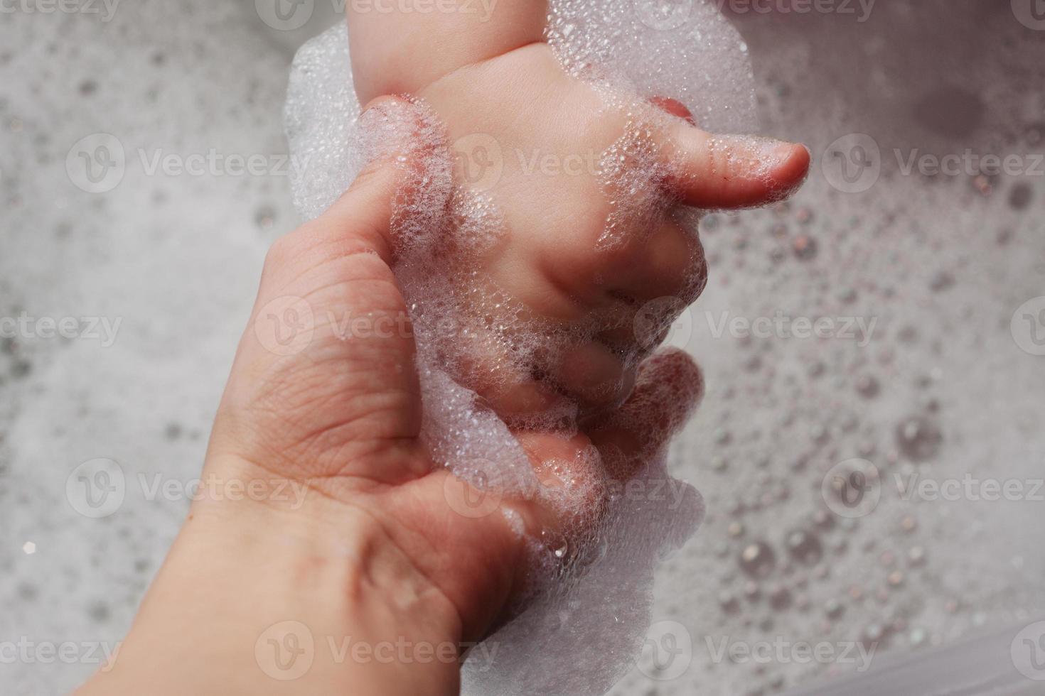 Mutter hält die Hand in einer Badewanne mit Schaum foto