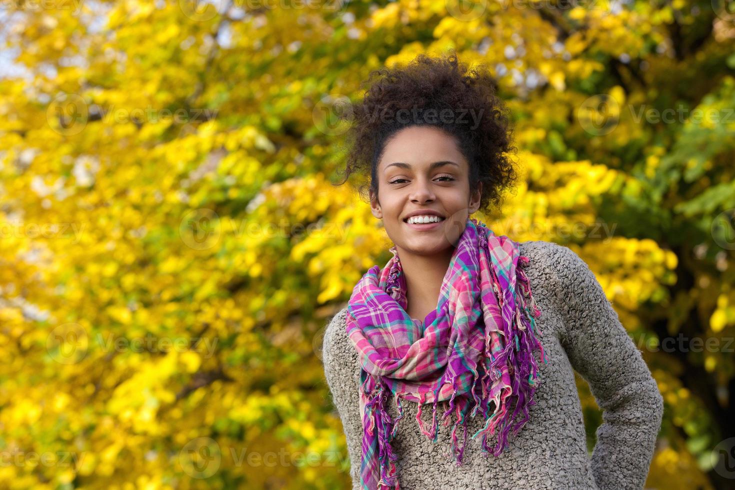 schöne junge schwarze Frau, die im Herbst draußen lächelt foto