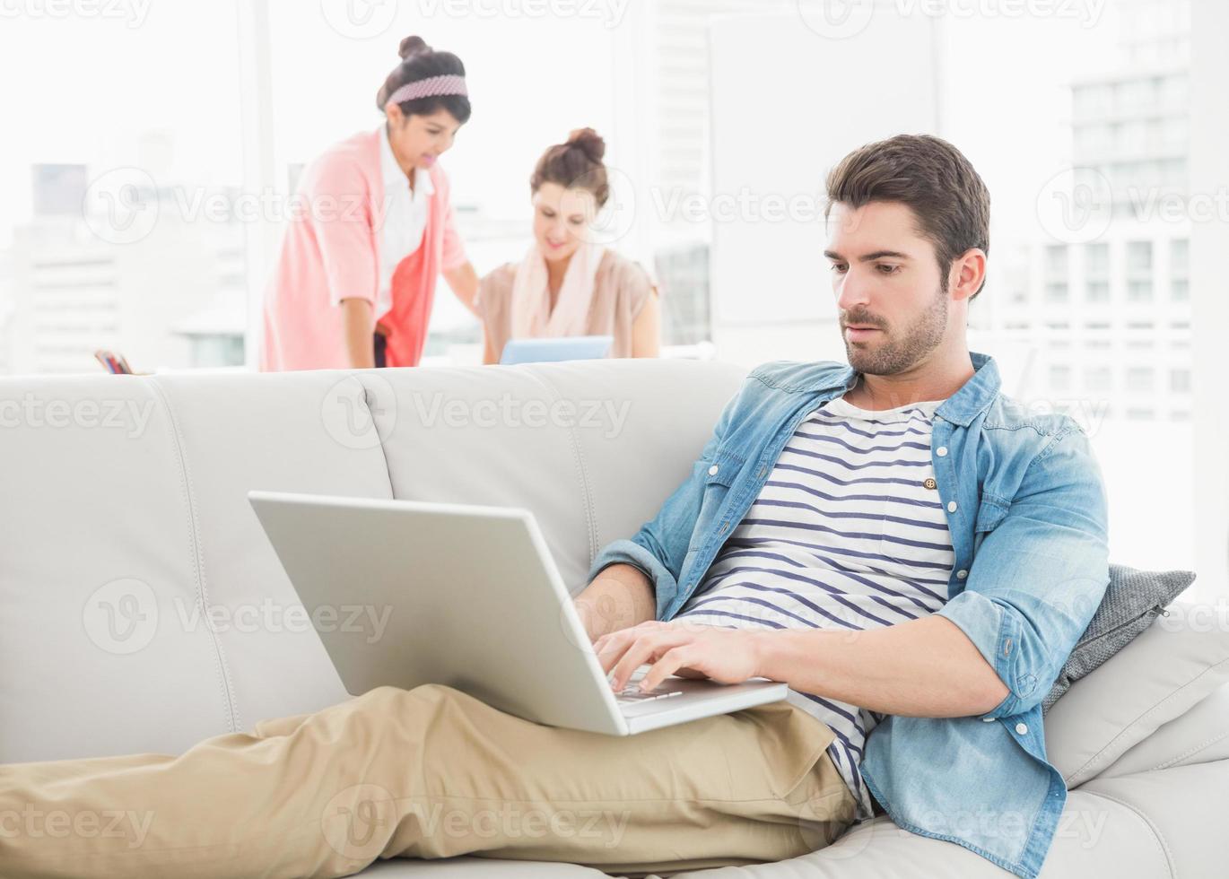 fokussierter Geschäftsmann mit Laptop auf Sofa foto