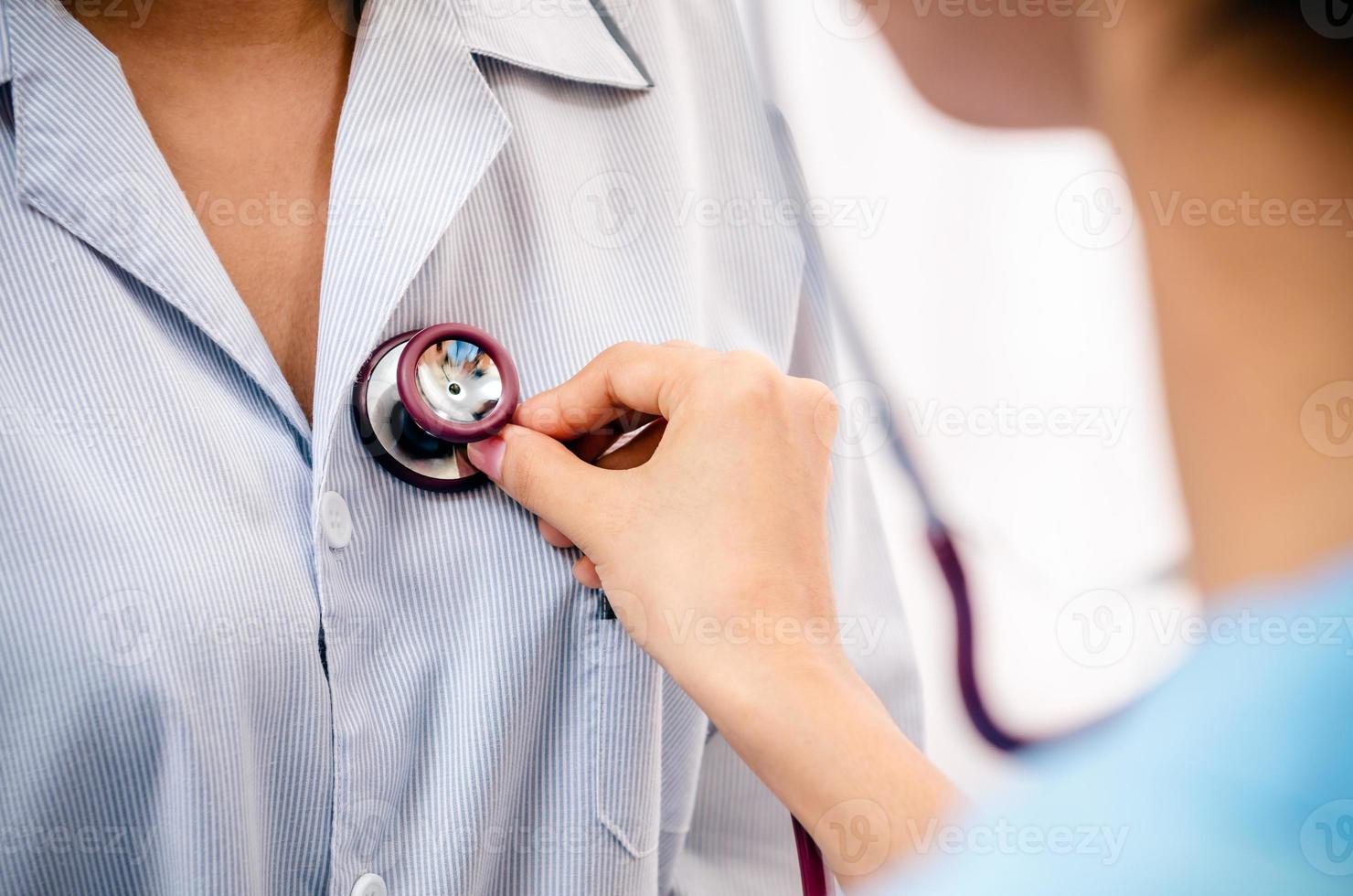Arzt hört auf das Herz des Patienten foto