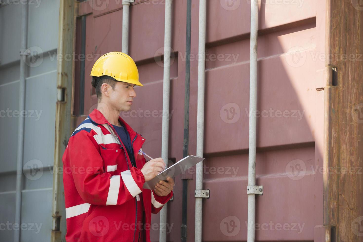 männlicher Arbeiter, der Frachtcontainer inspiziert foto