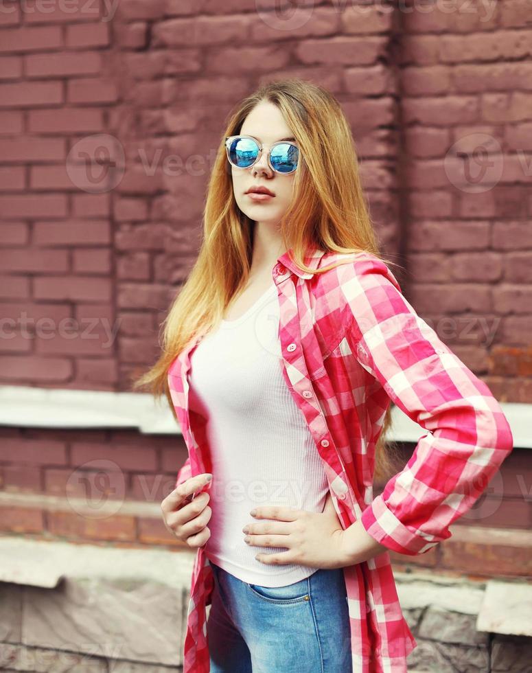 Porträt junges Mädchen, das ein kariertes Hemd und eine Sonnenbrille ove trägt foto