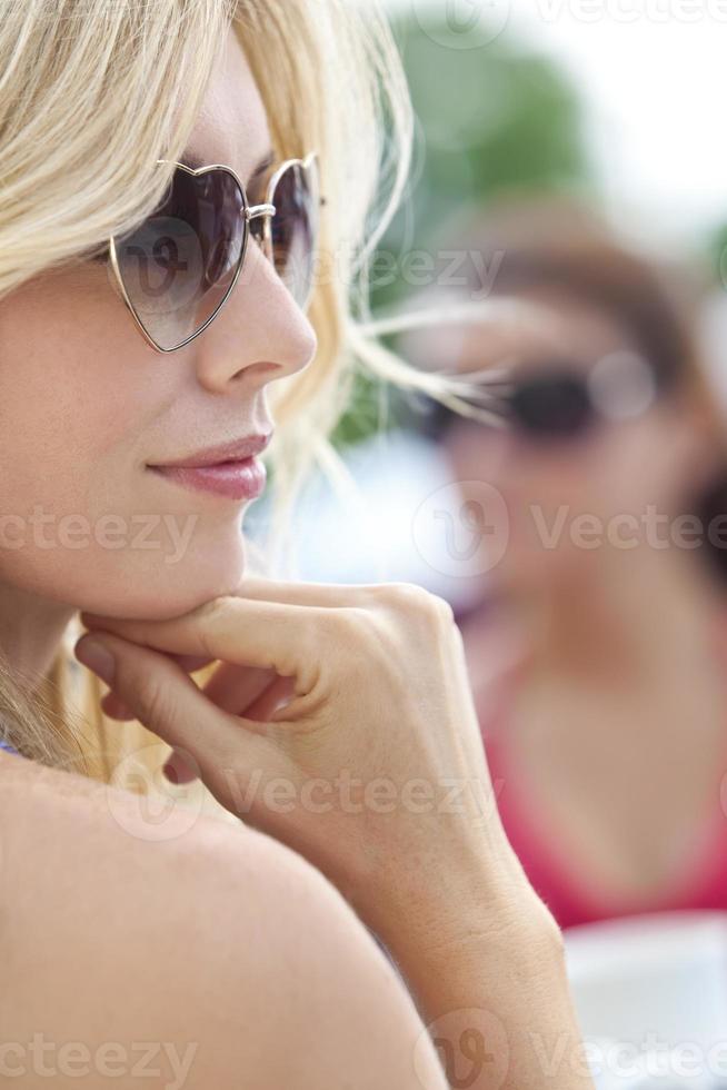 Seitenprofil der blonden Frau in herzförmiger Sonnenbrille foto