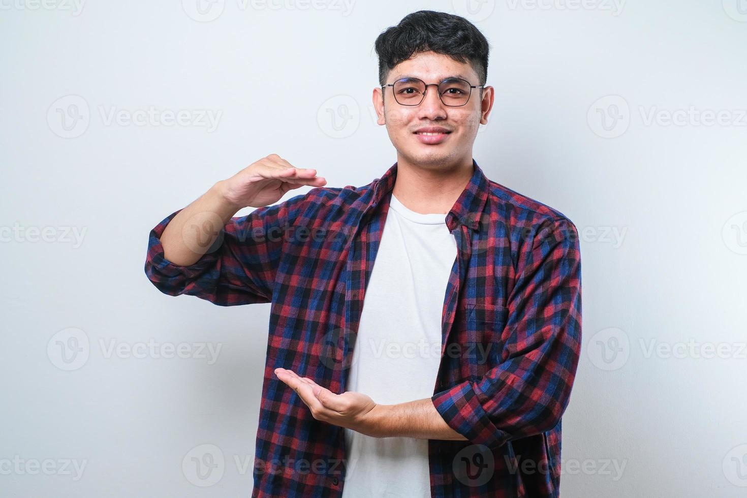 Schöner asiatischer Mann, der mit Händen gestikuliert, die große und große Zeichen zeigen, Symbol messen. lächelnd in die Kamera blicken. Messkonzept. foto