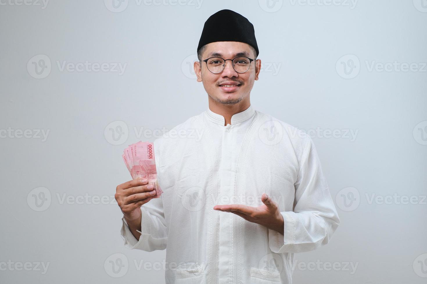 asiatischer muslimischer mann lächelt glücklich, während er papiergeld hält foto