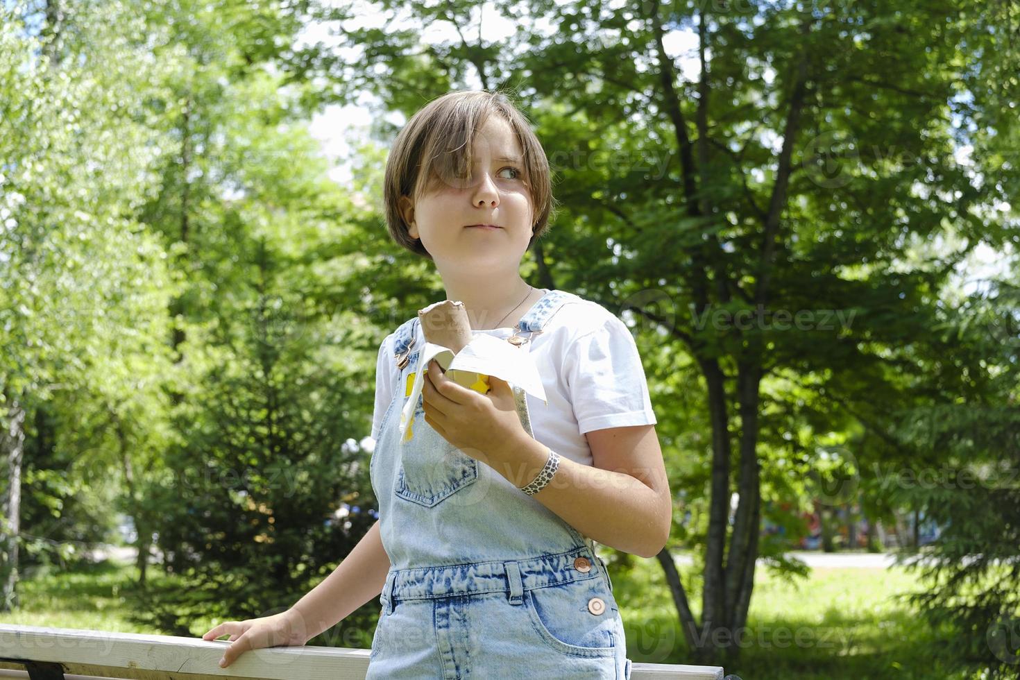 Ein junges Mädchen, das an einem Sommertag im Park spazieren geht, um Eis zu genießen foto