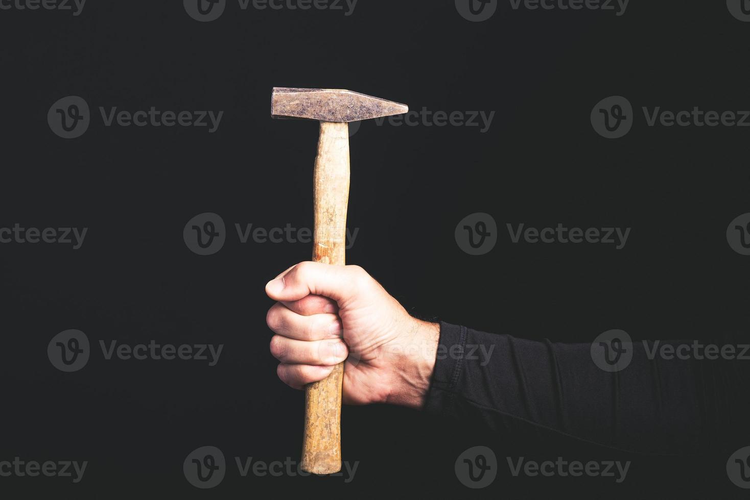 Hammer in der Hand eines Mannes auf schwarzem Hintergrund - Wartungsservice-Konzept foto