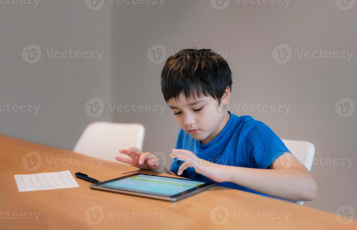 Schulkind lernt Online-Klassenzimmer zu Hause, Kind benutzt Tablet für Hausaufgaben, Junge studiert Online-Videoanruf, E-Learning oder Homeschooling-Bildungskonzept foto