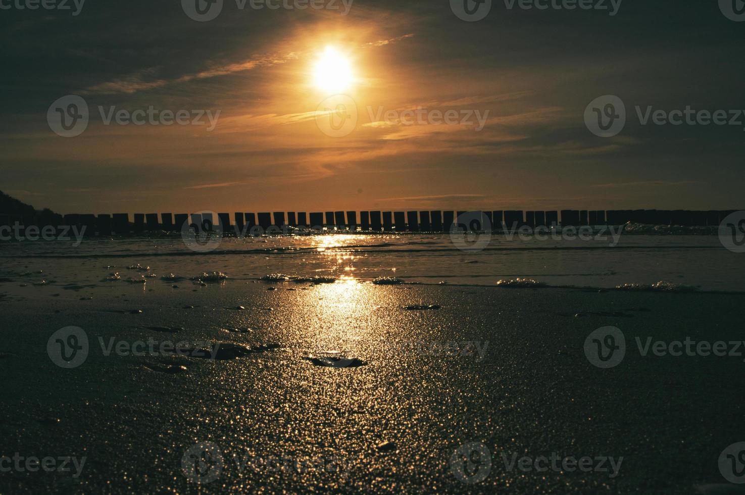 sonnenuntergang in zingst am meer. rot-orangefarbene Sonne geht am Horizont unter. Möwen kreisen am Himmel foto