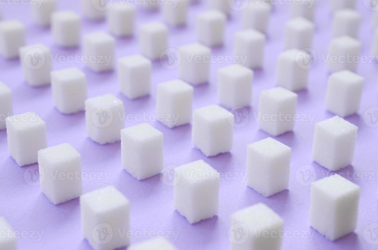 Viele kleine Zuckerwürfel sind auf einem violetten Hintergrund aufgereiht. foto
