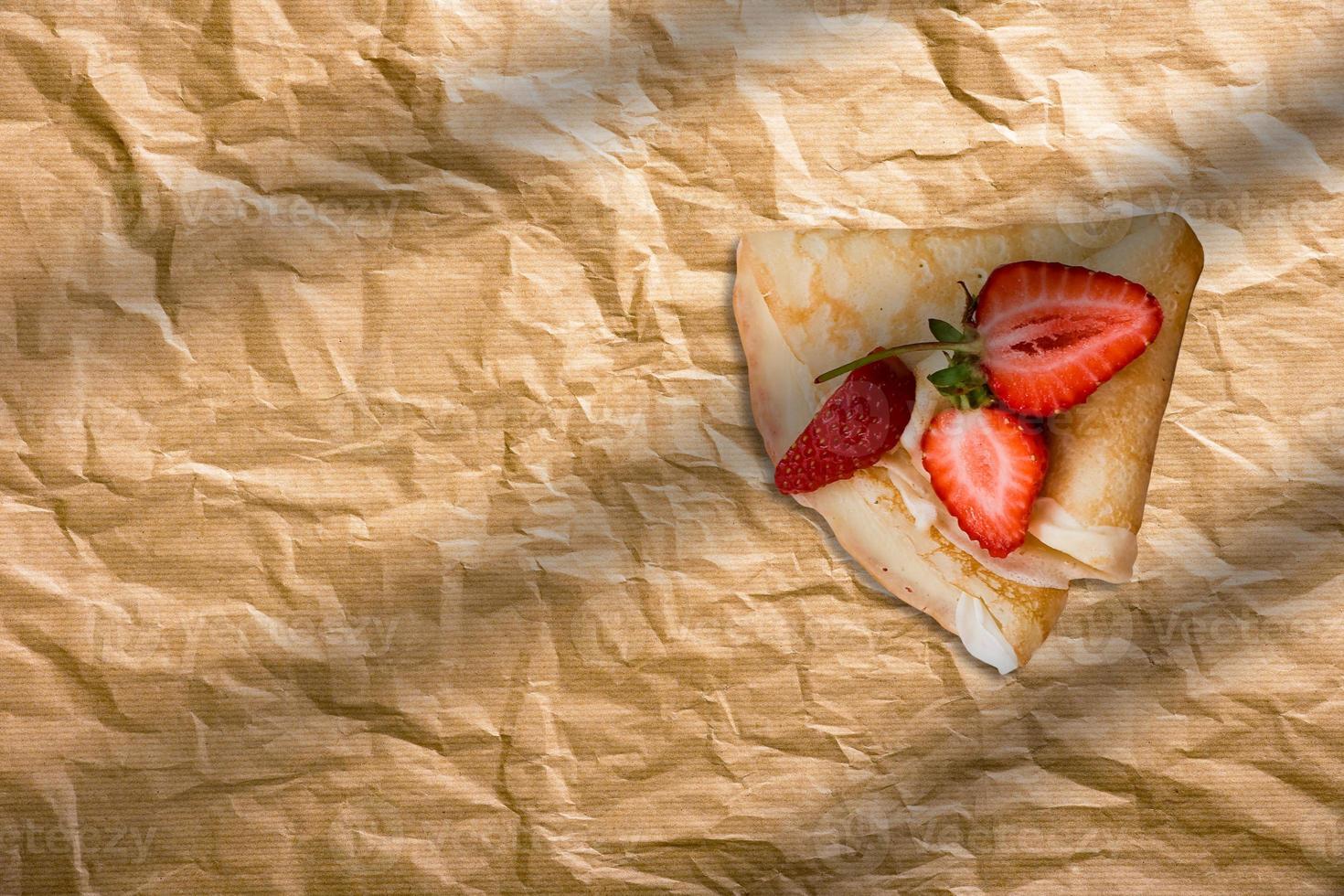 frischer hausgemachter Pfannkuchen mit Erdbeerscheiben auf Backpapier. französisches bäckereikonzept foto